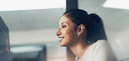 Photo of a smiling brunette woman looking left toward a monitor