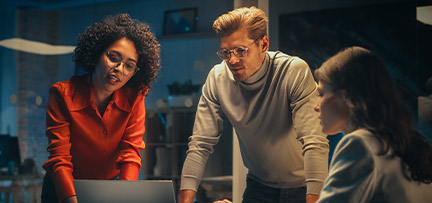 Two women and a man looking at a laptop