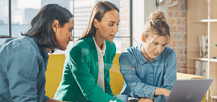 Man and two women look at laptop